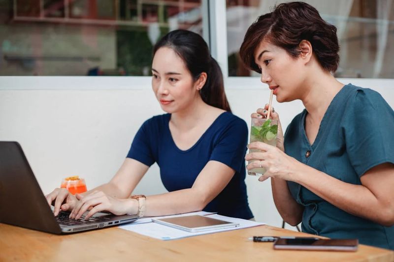 Two Women Working Patiently at a Laptop
